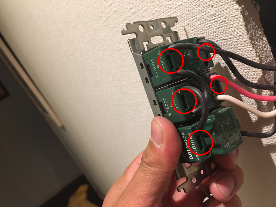スイッチの裏側に繋がっている配線と配線取り外し用の穴に赤丸の目印